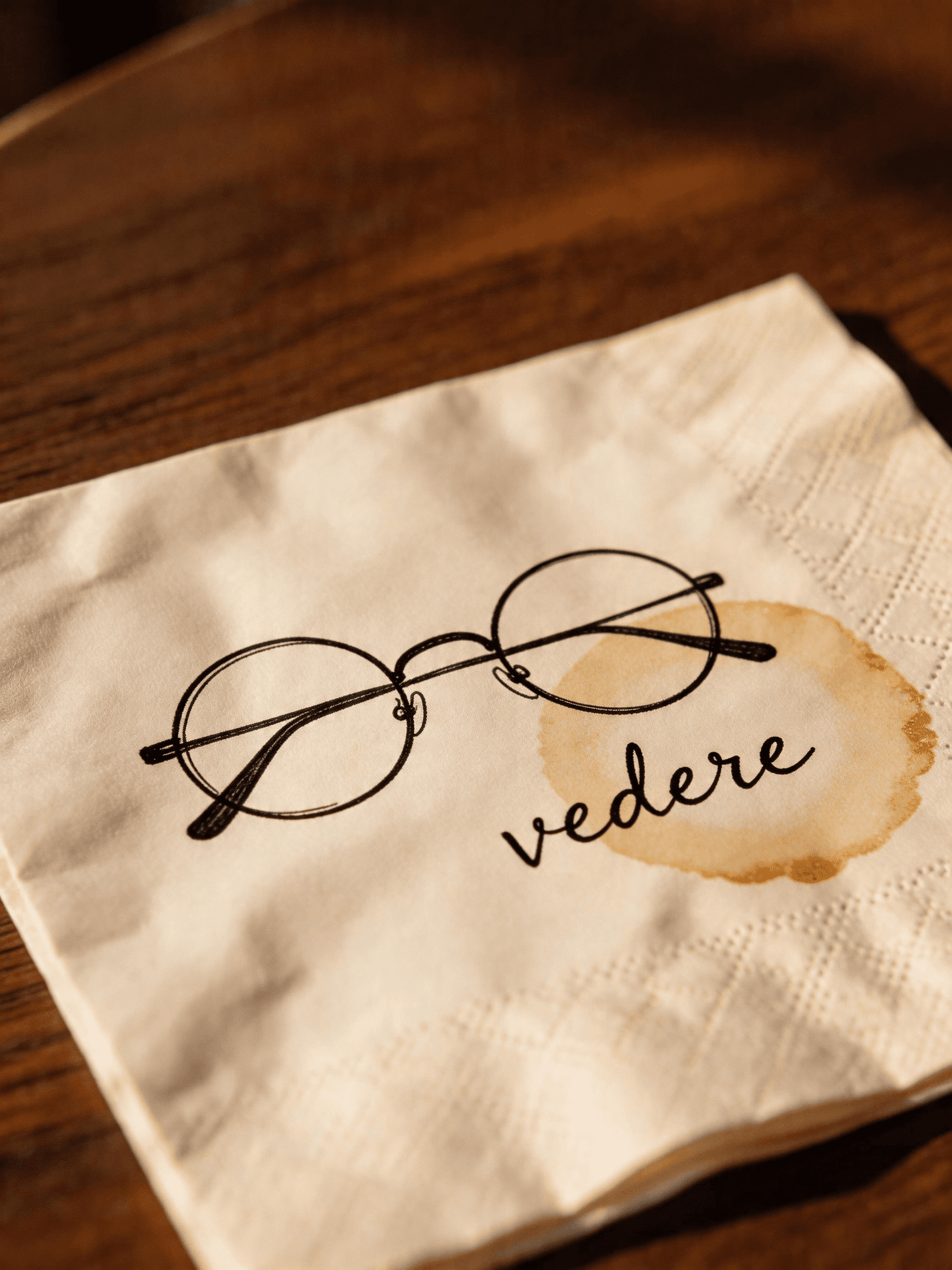 The napkin sketch of a single-lens pair of glasses, with the word vedere