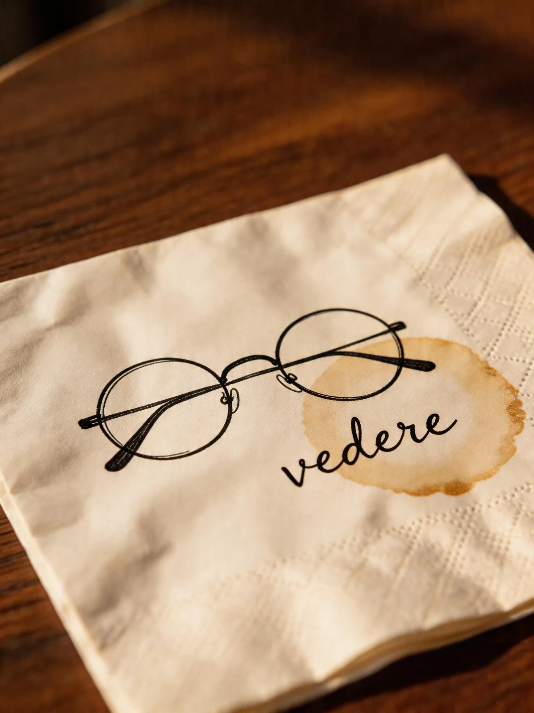 The napkin sketch of a single-lens pair of glasses, with the word vedere